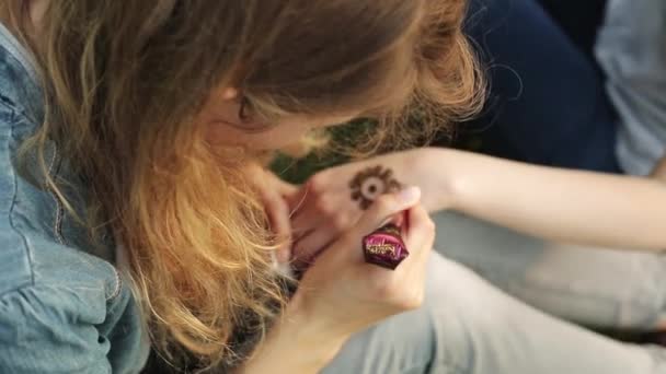 Femme faisant mehendi floral sur une main avec du henné sur une table . — Video