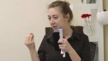 Profesyonel makyaj sanatçısı bir masterclass makyaj tekniklerini öğretir. Bir sarışın ile çok renkli işaretli bir güzellik stüdyosu sınıfında konuşma onun elinde büyük eyes.