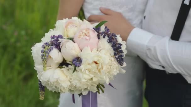 Beau bouquet de différentes couleurs dans les mains de la mariée dans une robe blanche. Heureux couple marié avec des fleurs de mariage . — Video