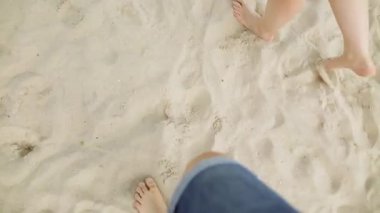 Bakış açısı ile birlikte altın kum adım denizde plaj genç bir çift. Erkek ve kadın okyanus yakın yürüyüş bacaklar. Kumlu sahilde gidiş çiftinin çıplak ayak. Yaz tatili.