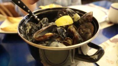 El midye bir limon suyu gorgonzola peyniri bir sos dökülüyor. Lezzetli midye açık hava deniz ürünleri Restoran içinde yemek kadın.