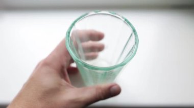 Erkek elinde boş yönlü cam. Genç adam cam temiz olup olmadığını denetleme. O her yönden bakıyor.