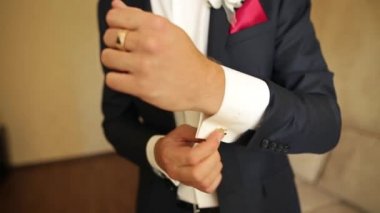 Şık adam şık kol düğmeleri giyer. Elinde düğün damat takım elbiseli hazırlanıyor.