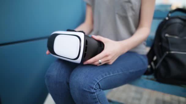 Будущее сейчас. Молодая женщина на лестнице играет в игру в VR-очках. Молодая белая женщина прикасается к чему-то с помощью современных очков виртуальной реальности на синем фоне . — стоковое видео
