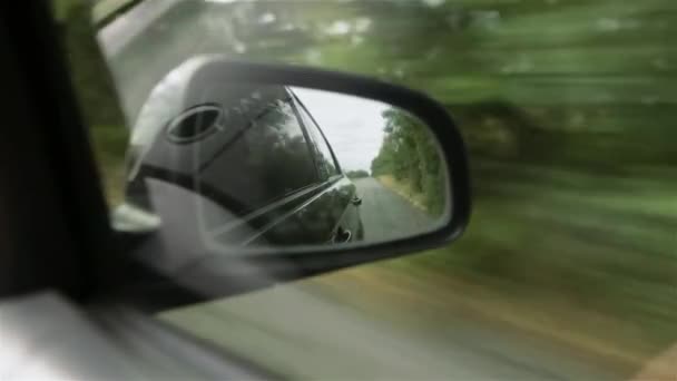 Movement in the car side mirror, view of the road. Reflection of a broken post-Soviet route with many pits. — Stock Video