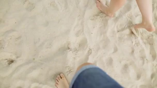 Ponto de vista do jovem casal pisando juntos na areia dourada na praia do mar. Pernas masculinas e femininas a caminhar perto do oceano. Pés de par descalços na costa arenosa. Férias . — Vídeo de Stock