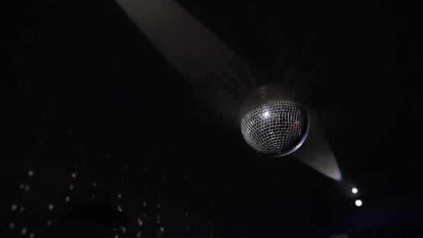 Mirror ball reflekterar vitt ljus. En vacker discokula med reflekterade rörliga strålar snurrar på en svart bakgrund i en nattklubb på fest. — Stockvideo