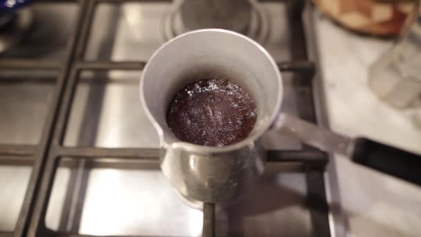 Café turco a ferver do cezve. Espuma densa em uma cafeteira de alumínio em um fogão a gás . — Vídeo de Stock