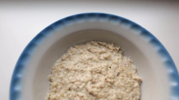 Gesundes Frühstück, Haferbrei mit Milch. Haferflocken gefüllt mit Milch in einer Fayence-Schüssel auf weißem Hintergrund. Bio-Lebensmittel für gute Gesundheit. — Stockvideo