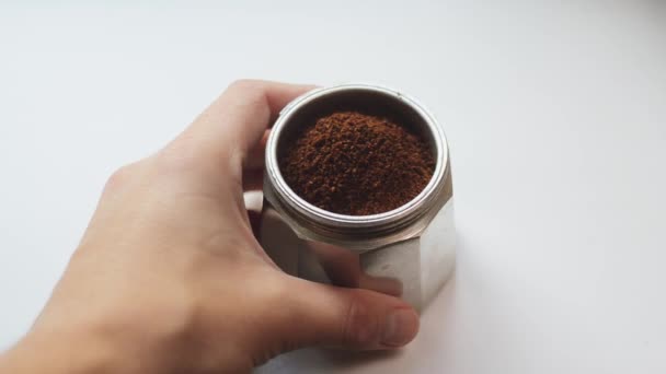 Giovane uomo mette sul tavolo la camera inferiore della macchina per il caffè con acqua e una miscela profumata appena macinata di caffè. Arabica o robusta per una mattinata allegra in moka pot italiano . — Video Stock