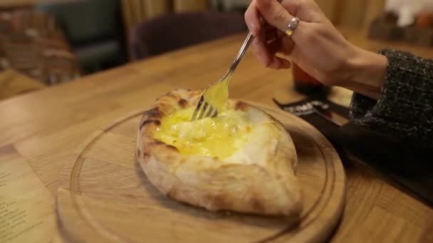 Hembra mezclando ingredientes de adjarian khachapuri con tenedor. Khachapuri es pan abierto relleno con queso y yema de huevo, plato tradicional de la cocina georgiana. De cerca. — Vídeo de stock