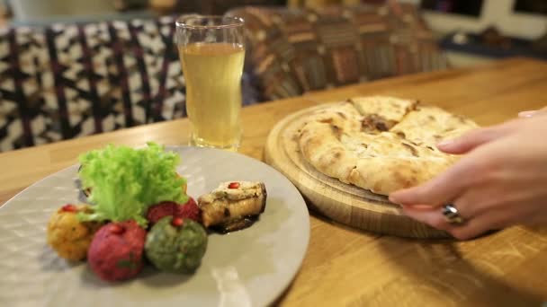 Woman hands takes a piece of traditional Georgian khachapuri dish with meat. Multi-colored Pkhali, Georgian dish with nuts and kubdari. — Stock Video