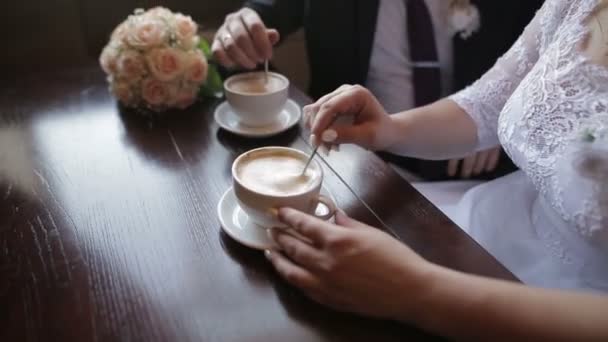 Mladý pár mluvit a pití kávy během snídaně v kavárně. Míchání cukru v cappuccino. — Stock video