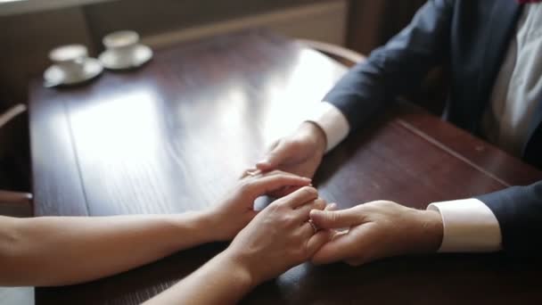 Un par de recién casados tomados de la mano en un café. Primer plano de las manos humanas . — Vídeo de stock