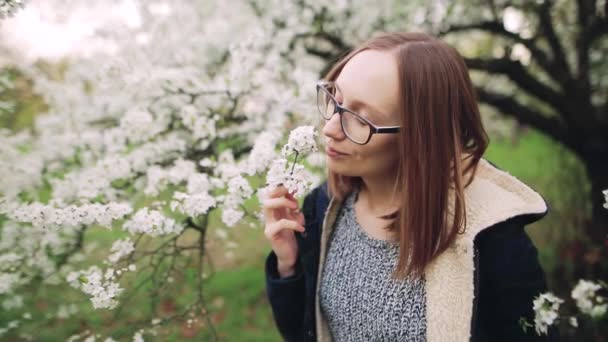 Mulher jovem feliz bonita desfrutando cheiro em um jardim de primavera florido — Vídeo de Stock