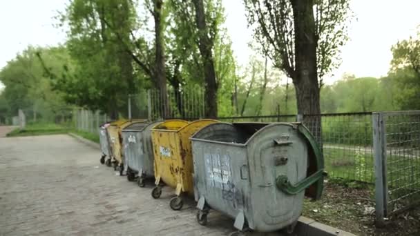 SUMY, UKRAINE - 04 мая 2018 года: Мусорные баки с мусором перед забором на улице в городе . — стоковое видео