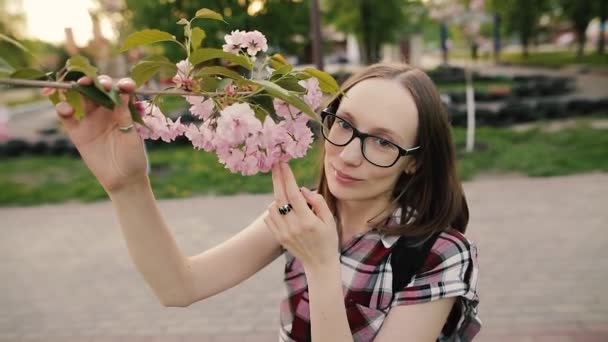 Chica feliz con flores de árbol de sakura. Concéntrate en la cara. Concepto de primavera. Movimiento lento . — Vídeos de Stock