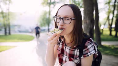 Hippi kız gözlük ve bir dilim pizza yeme rahat bir gömlek gülümseyen.