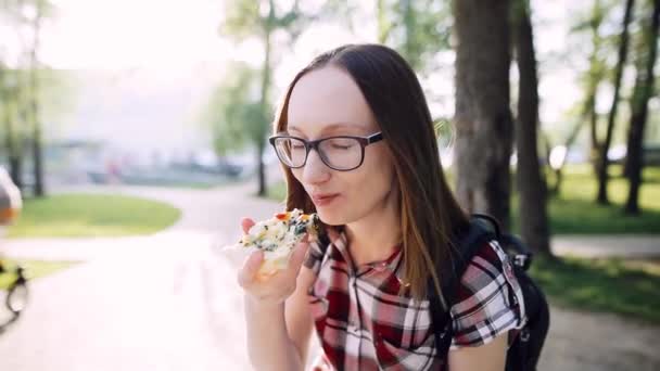 Kaukázusi csípő lány szemüvegét eszik egy szelet, vegetáriánus pizza, spenóttal. — Stock videók