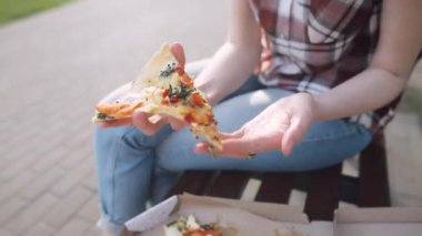 Detaylı kız bir parça taze pizza alır ve yiyor. Portre vurdu. Seçici odak.