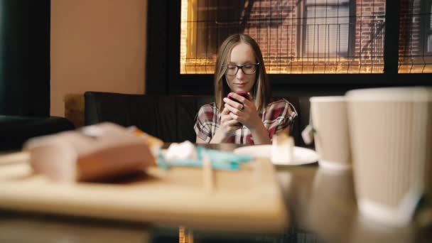 积极的年轻女子阅读有趣的信息智能手机在咖啡馆内部. — 图库视频影像