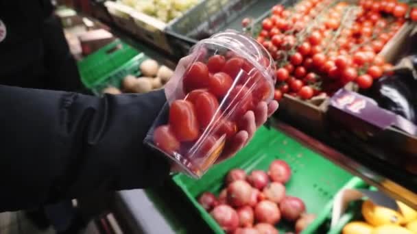 Φρέσκες βιολογικές επιλεγμένες ντομάτες στα χέρια ενός νεαρού κοριτσιού που επιλέγει αγροτικά προϊόντα σε τοπικό σούπερ μάρκετ. — Αρχείο Βίντεο