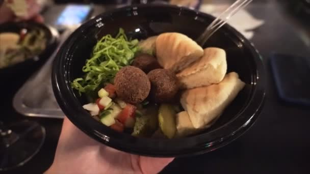 Falafel apetitoso com pão de pita e salada de legumes na placa nas mãos de um viajante . — Vídeo de Stock