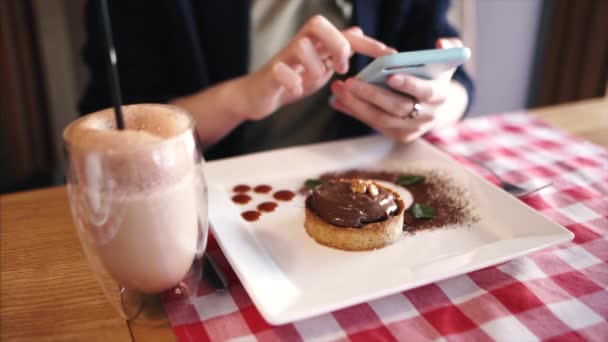 Chica de moda mensajes de texto en las redes sociales en un café, compartir sus fotos de alimentos. DOF poco profundo . — Vídeo de stock