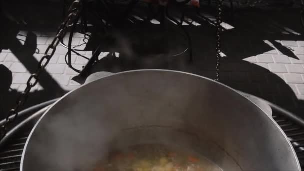 Vertical pan, frutos do mar e sopa de legumes em um grande caldeirão preto na rua, close-up . — Vídeo de Stock