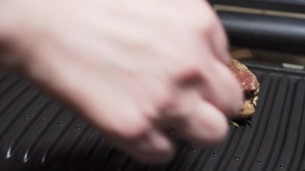 女性的手在烤架上把新鲜的迷迭香涂在牛排上. — 图库视频影像
