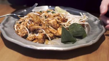 Kız ünlü Tayland yemeğinin üzerine şeker serper - erişteli Pad Thai, tavuk, tofu, tamarind sosu, soya lahanası. 