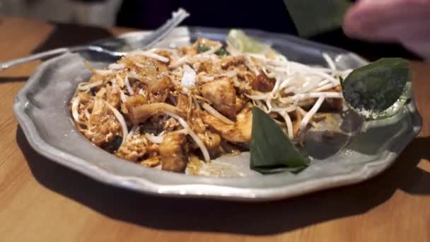 Menina acrescenta amendoins ao Pad Thai - famoso prato tailandês . — Vídeo de Stock