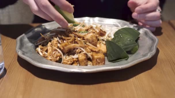 Flicka pressar lime i en pad tai - berömd thailändsk maträtt. Närbild skott. — Stockvideo
