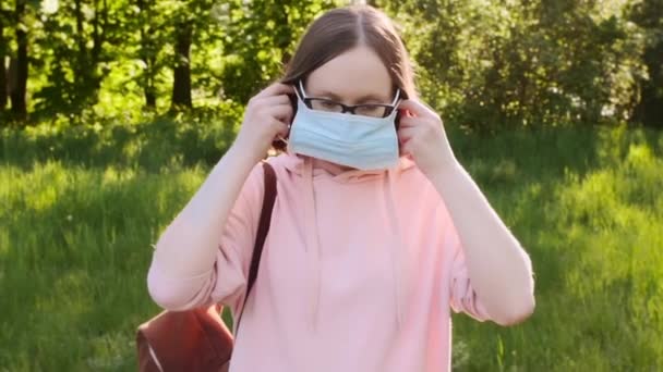 Young trendy girl wearing protective medical mask outdoors in the park. — Stock Video