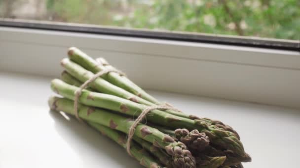 A bunch of fresh organic green asparagus on the windowsill. — Stock Video