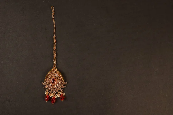 Authentiques bijoux indiens traditionnels Tika sur fond sombre. Portez-le à la tête lors de mariages, festivals et autres occasions. Image très utile pour le site Web, l'impression et l'application mobile . — Photo