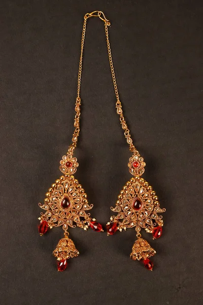 Autentiska traditionella indiska smycken örhängen på mörk bakgrund. Bär i öronen i bröllop, festivaler och andra tillfällen. Mycket användbar bild för webbplats, utskrift och mobil ansökan. — Stockfoto
