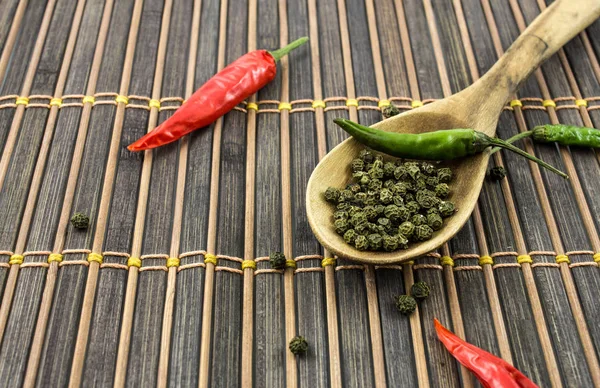 Baharat ve rustik bir arka plan üzerinde tahta kaşık biber biber.