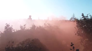 Sahada duman içinde koşan ve düşen asker siluetlerinin yavaşlaması. Havan topu altında.