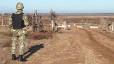 Silahlı askerler bölgede devriye geziyor. Bir araç sürüsü korunan bölgeye yaklaşıyor..