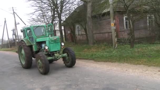 Starina, Fehéroroszország, 2019. október. Egy öreg zöld traktor száguld át a falun. Házi készítésű autó. Farmer technika. Betakarító berendezés 4k. — Stock videók