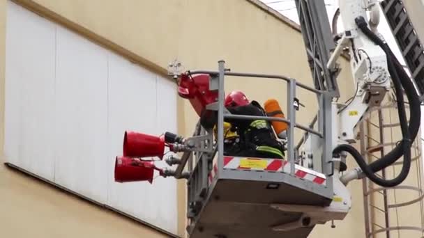 Os socorristas sobem em ascensão para eliminar o fogo. Bombeiros batalham fogo em chamas. Bombeiro com aparelho respiratório autónomo que sobe escada aérea através do fogo acima — Vídeo de Stock