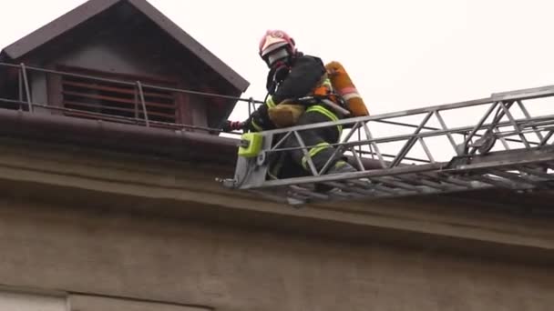 Räddarna reser sig på uppgång för att eliminera elden. Brandmän slåss mot brinnande husbrand. Brandman med inbyggd andningsapparat klättrar antenn stege genom ovan eld — Stockvideo