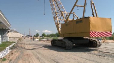 Güçlendirilmiş beton yapılar ve köprüler için yüksek vinç. İnşaat alanında çalışanlar. Ağaçlar arasında su 4K boyunca bir otoyol inşaatı
