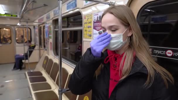 2020ベラルーシのミンスク 地下鉄で医療マスクをした若い女性 感染症からの保護コロナウイルスは公共交通機関で流行しています 女の子はマスクを修正し 懸念と周り4K — ストック動画
