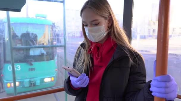 窓の近くの公共交通機関に乗り 携帯電話を使用する保護マスクを身に着けているパンデミック 若い女性 医療マスクの女性がバスに乗っている 自由運動の禁止 コロノウイルス隔離 — ストック動画