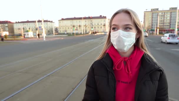 美しい娘が街中の路上にマスクをつけて日没時に車を通り過ぎる パンデミック時に保護マスクを着用する意識的な市民 Covid 隔離4K — ストック動画