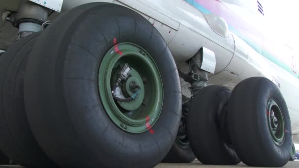 飛行場で乗客用飛行機のタイヤを閉じてください メカニズムの外側から大規模な旅客機のシャーシのショット 滑走路4Kに立つ飛行機の大きな車輪 — ストック動画