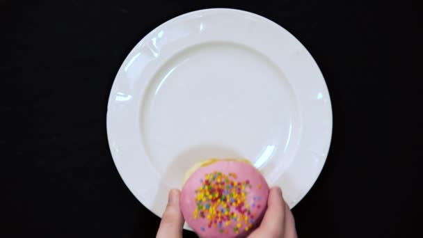배경에 손으로 맛있고 도넛을 접시에 얹는다 위에서 화려하게 뿌려진 클로즈업 — 비디오