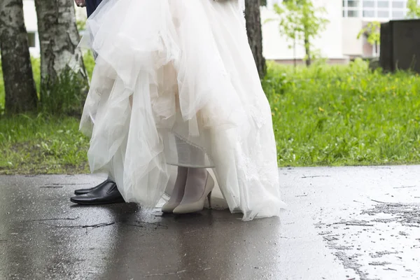 Sposo in giacca e cravatta e sposa in abito da sposa stand sulla strada nel bosco — Foto Stock